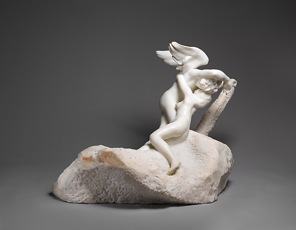 Two pale marble figures rise from a broad, rough block. One arches upward beneath the other’s lifted arm and wing; smooth bodies meet unfinished stone.